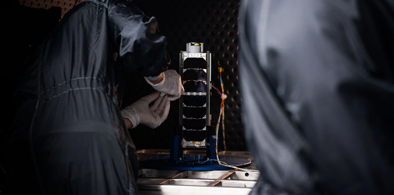 Undeplyed 3U Deployable Solar Panel in testing environment and two people assembling it