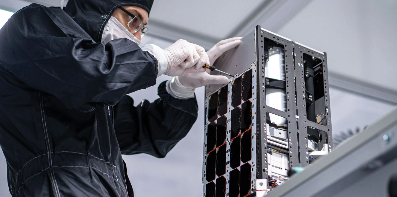 Engineer assembling and securing solar panels on a 16 cubesat during cleanroom integration