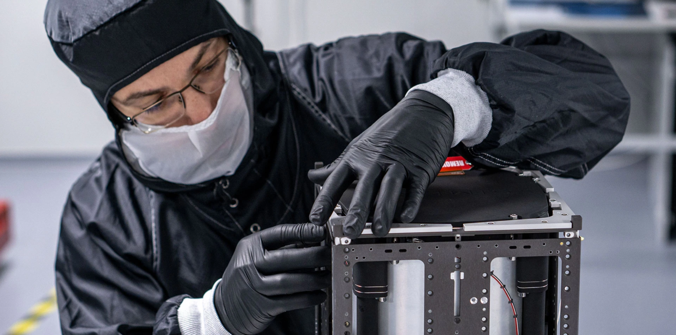 Engineer integrating structural components of a 16 cubesat during cleanroom assembly