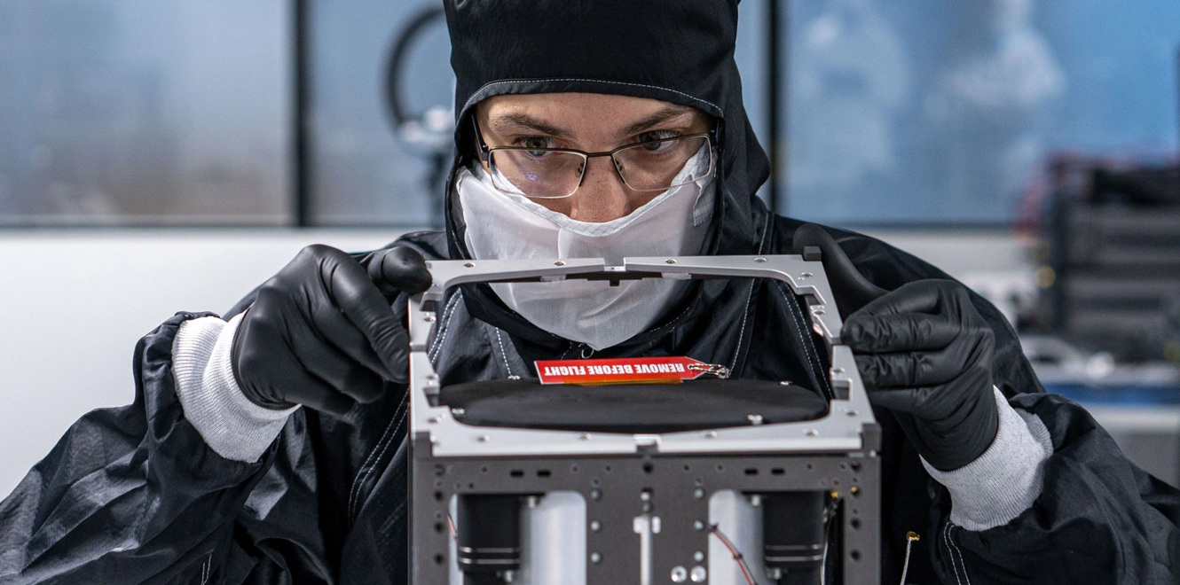 Engineer assembling a 16 cubesat structure in a cleanroom environment