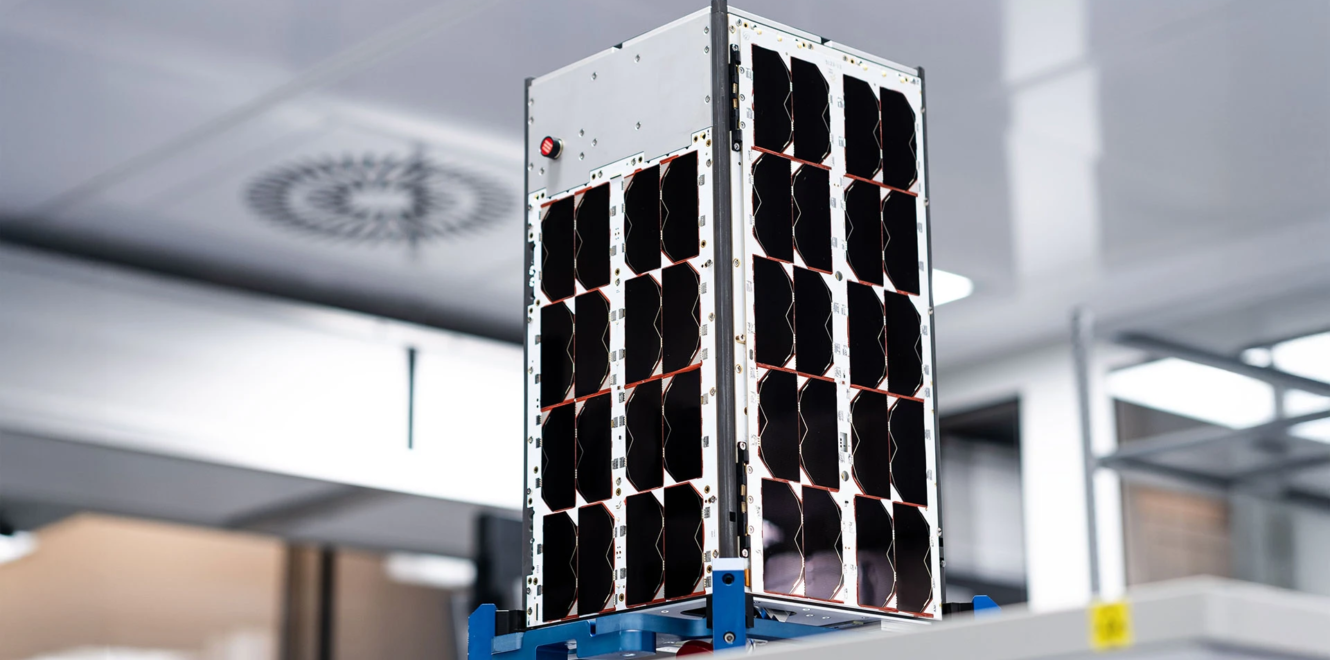 16 cubesat prototype with body-mounted solar panels undergoing ground testing in a cleanroom environment